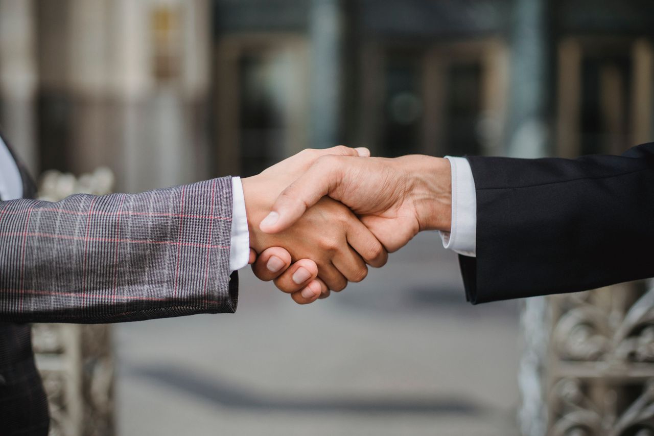 our-story-02 A close-up of two businesspeople shaking hands, symbolizing cooperation and partnership.